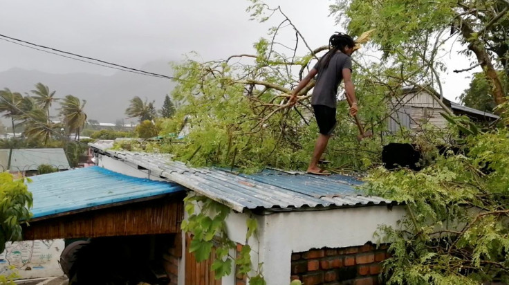 A man removes a fallen branch from the roof of a house, amidst Cyclone Emnati, in Fort Dauphin, Madagascar February 23, 2022, in this still image obtained from a social media video. Courtesy of Louise du Plessis, Twitter @Louisedp3137/via REUTERS