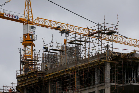 Construction workers work beneath cranes on a building project in Cape Town, August 31, 2015. 