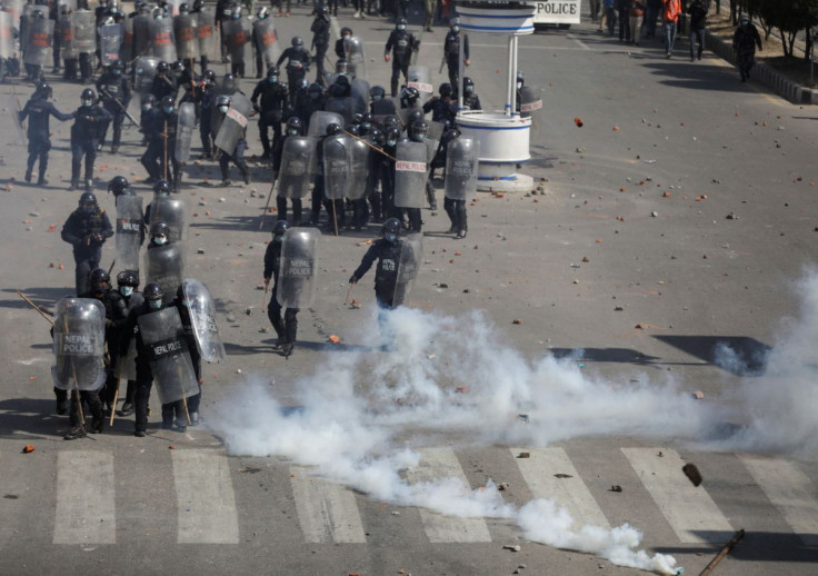 Riot police personnel take cover as demonstrators hurl back tear gas cans and stones towards them during a protest against the $500 million U.S infrastructure grant under the Millennium Challenge Corporation (MCC) near the parliament in Kathmandu, Nepal F