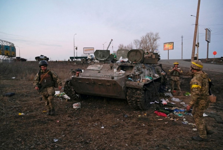 Ukrainian servicemen are seen next to a destroyed armoured vehicle, which they said belongs to the Russian army, outside Kharkiv, Ukraine February 24, 2022. 