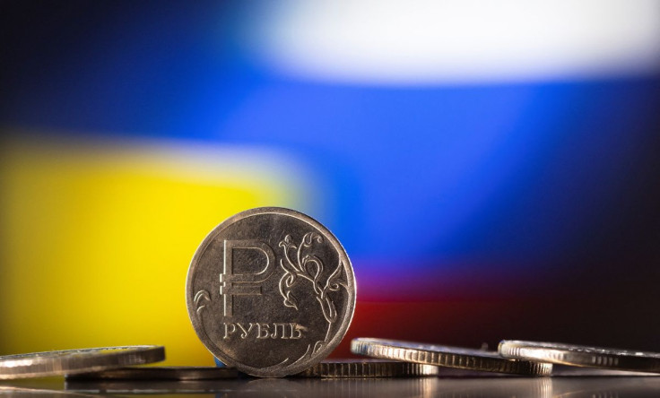 Russian Rouble coins are seen in front of displayed Ukrainian's and Russia's flag colours in this illustration taken, February 24, 2022. 