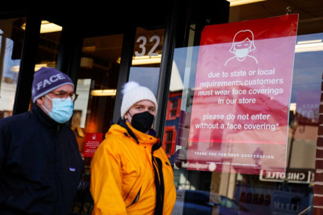 People wearing protective face masks walk past a business displaying a sign requiring face coverings during the coronavirus disease (COVID-19) pandemic in Washington, U.S. January 31, 2022.    