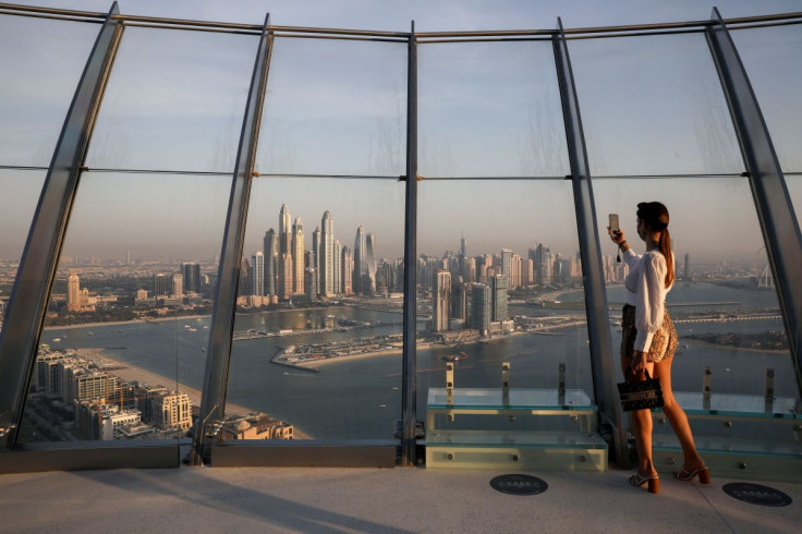 A woman takes a picture with a smartphone of the upscale Marina district from the Palm Tower in Dubai, United Arab Emirates, June 9, 2021. Picture taken June 9, 2021.