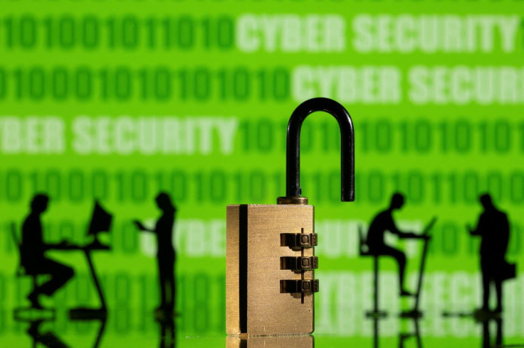 3D printed models of people working on computers and padlock are seen in front of a displayed CYBER SECURITY words and binary code in this picture illustration taken, February 1, 2022.