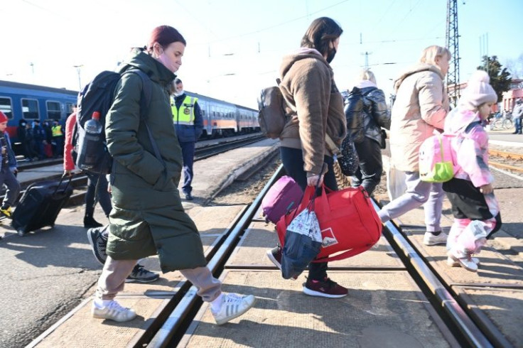 Refugees cross the railway tracks after arriving at Zahonyi railway station close to the border with Hungary