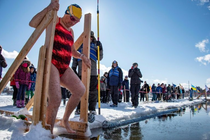 Ginny Peck, 76, steps into the water as she prepares to swim the 50-meter freestyle race during the Memphremagog Winter Swimming Festival in Newport, Vermont, on February 26, 2022
