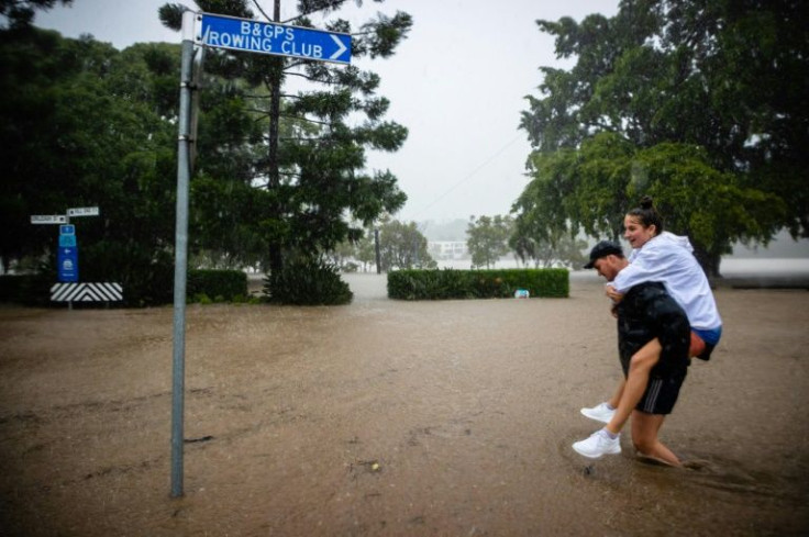 A couple wades through a waterlogged street on the banks of the overflowing Brisbane River