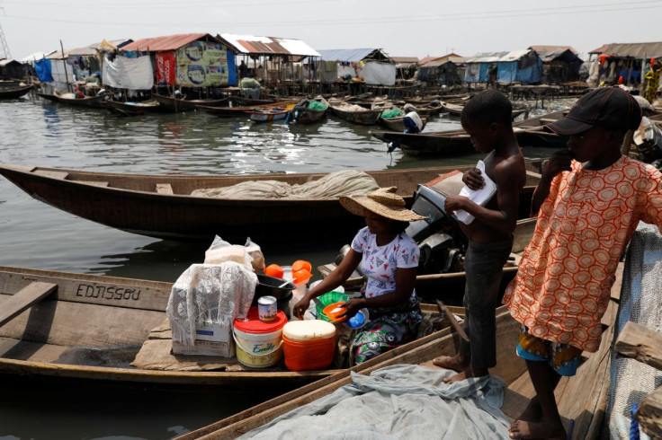 A woman sits in a canoe as she sells food to children at the Makoko fishing community on the Lagos Lagoon, Nigeria February 26, 2022. Picture taken February 26, 2022.