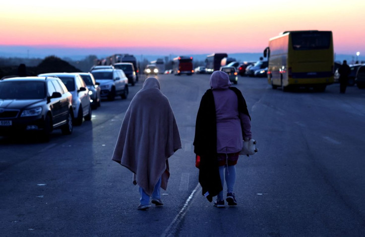 Women covered in blankets walk along a street after they fled the Russian invasion of Ukraine at the border checkpoint in Medyka, Poland, February 28, 2022.