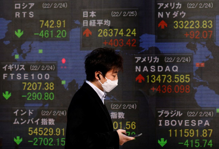 A man wearing a protective mask, amid the coronavirus disease (COVID-19) outbreak, walks past an electronic board displaying Russian Trading System (RTS) Index, Japan's Nikkei index and the Dow Jones Industrial Average outside a brokerage in Tokyo, Japan,