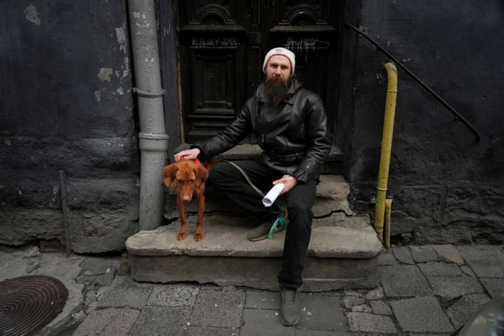 Video producer Yuri Futalo poses for a picture with his dog as he is collecting documents necessary to purchase a gun as Russia's invasion of Ukraine continues, in Lviv, Ukraine, March 1, 2022.   