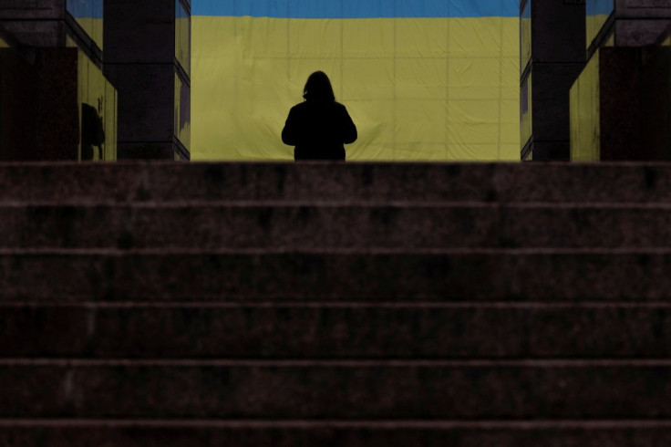 A resident stands in front of a Ukrainian national flag as part of "Unity Day," in downtown Kyiv, Ukraine February 16, 2022.