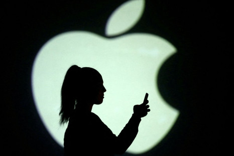 Silhouette of mobile user is seen next to a screen projection of Apple logo in this picture illustration taken March 28, 2018.  