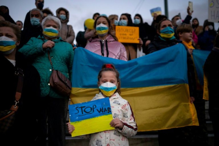 Ukrainians and supporters hold placards and a Ukraine national flag during a demonstration against the Russian invasion of the Ukraine in front of the Greek Parliament in Athens, on March 1, 2022