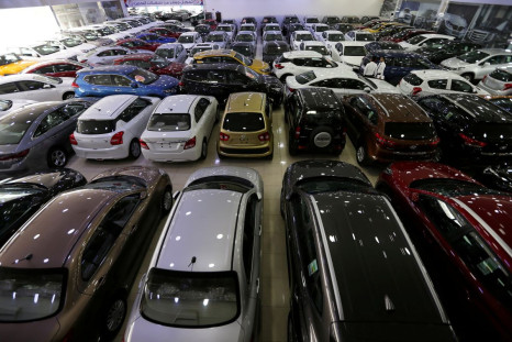 Auto dealers stand between the cars displayed for sale at a second hand car showroom Shoneez Motors in Sanabis, west of Manama, Bahrain, April 10, 2019. 