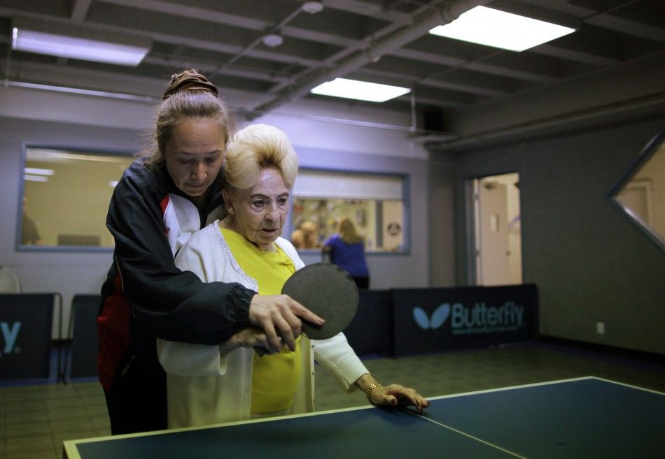 A holocaust survivor is helped by her coach as she plays ping pong at a program for people with Alzheimer039s and dementia in Los Angeles