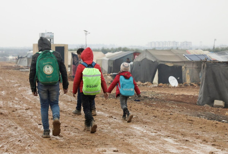 Internally displaced Syrians walk together near tents at a camp in Azaz, Syria March 1, 2022. Picture taken March 1, 2022. 