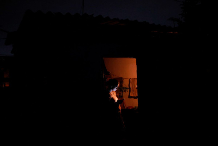 A woman checks her mobile phone while standing by the door at her home during the seven hours power outage in Colombo, Sri Lanka, March 2, 2022.