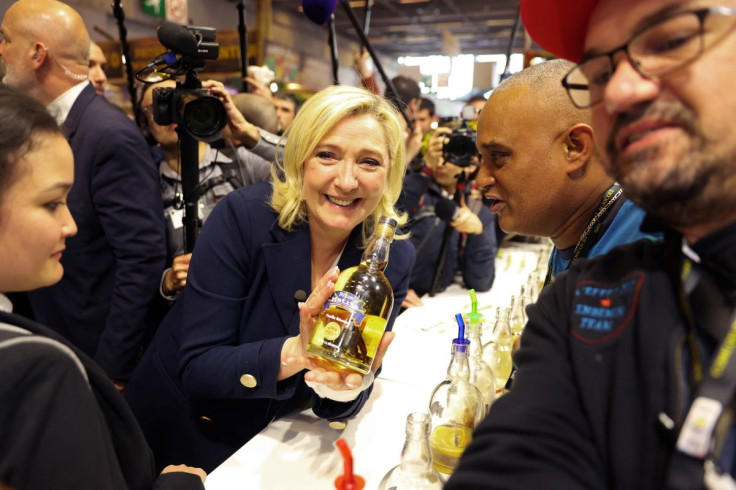 Marine Le Pen, leader of French far-right National Rally (Rassemblement National) party and candidate for the 2022 French presidential election, holds a Rhum bottle as she poses during a visit at the 58th International Agriculture Fair (Salon de l'Agricul