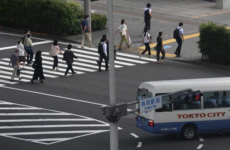 Workers cross a road during the morning rush hour, ahead of the Tokyo 2020 Olympic Games that have been postponed to 2021 due to the coronavirus disease (COVID-19) pandemic, in Tokyo, Japan, July 15, 2021. 