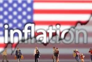 Small figurines are seen in front of displayed word "Inflation", U.S. flag and rising stock graph in this illustration taken February 11, 2022. 