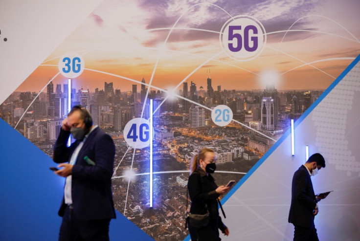 Visitors use their mobile phones next to a 5G advertising banner during the GSMA's 2022 Mobile World Congress (MWC), in Barcelona, Spain, March 2, 2022.