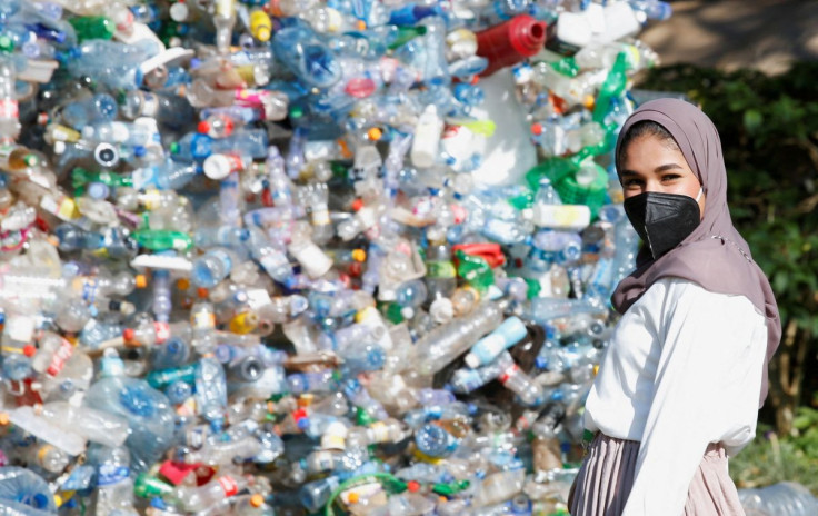 A delegate poses for a photograph near a 30-foot monument dubbed "turn off the plastic tap" by Canadian activist and artist Benjamin von Wong, made with plastic waste, at the venue of the Fifth Session of the United Nations Environment Assembly (UNEA-5), 