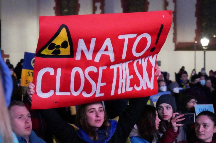 A woman holds a placard as people watch Ukrainian President Volodymyr Zelenskiy on a screen addressing anti-war demonstrations in several European cities including Frankfurt, Vienna, Lyon, Tbilisi, Vilnius and Prague, as Russia's invasion of Ukraine conti