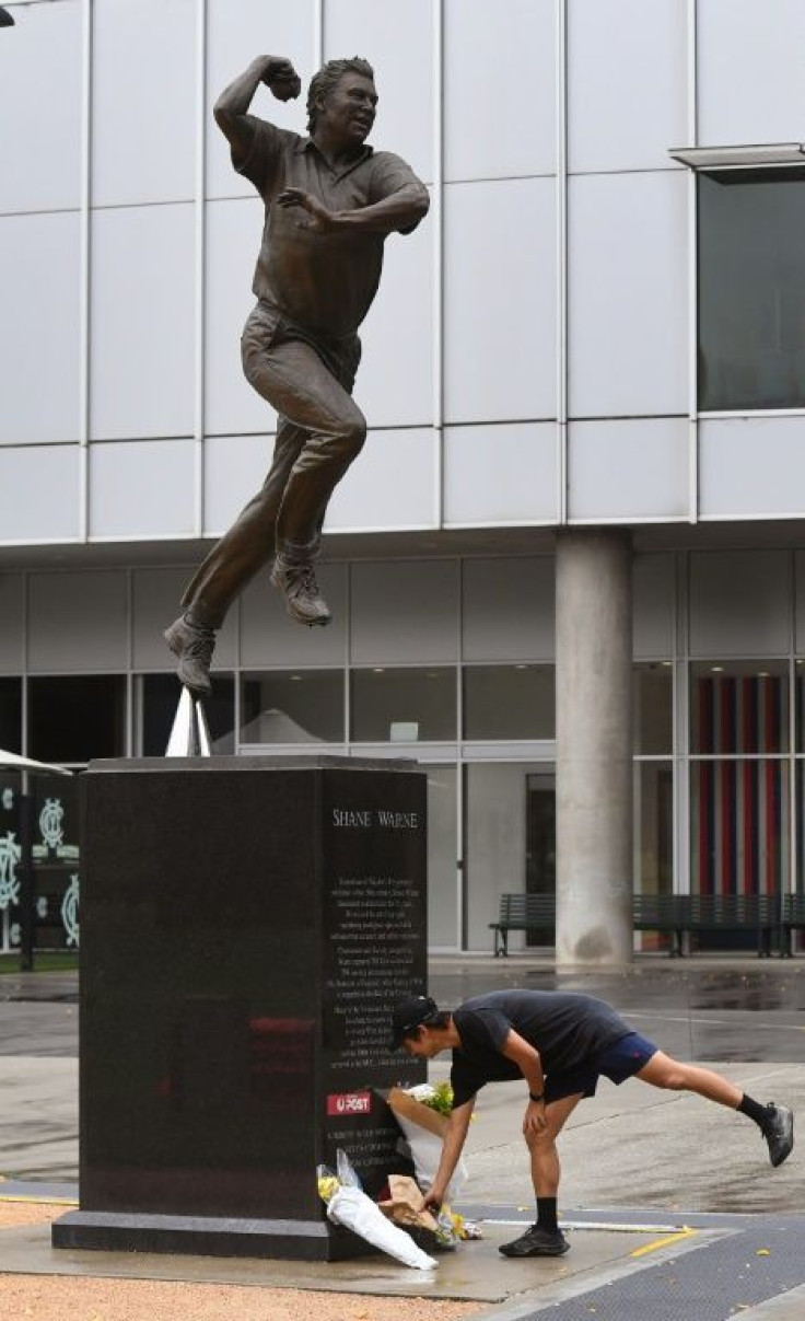 People place flowers at a statue of former Australian cricketing great Shane Warne outside the Melbourne Cricket Ground (MCG) in Melbourne on March 5, 2022. Australia cricket great Shane Warne -- one of the best Test players of all time -- has died of a s
