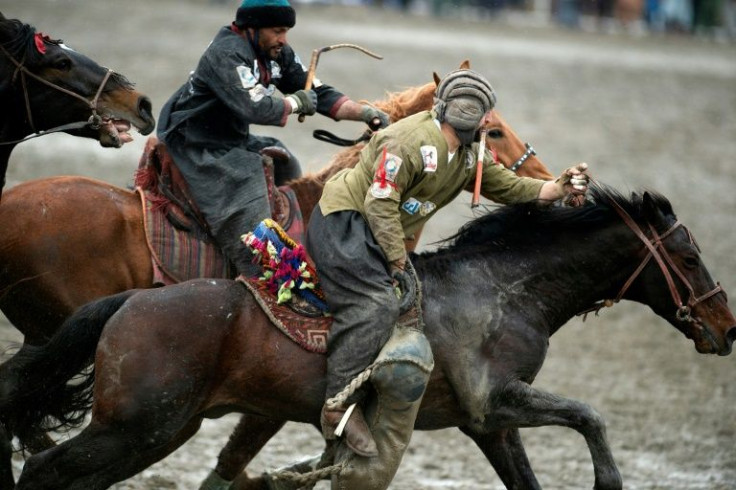 A Kunduz horseman, artificial goat carcass in hand, races to the "circle of truth" pursued by a Kandahar rider during the grand buzkashi final