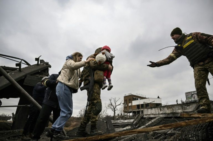 Ukrainian servicemen help civilians cross a bombed-out bridge to flee Irpin