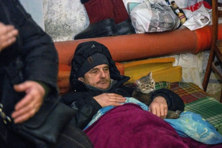 A man and his cat shelters in the basement of a building with some belongings and food, after Russian troops shelled the area in the second largest Ukrainian city of Kharkiv, in the east of the country on March 6, 2022