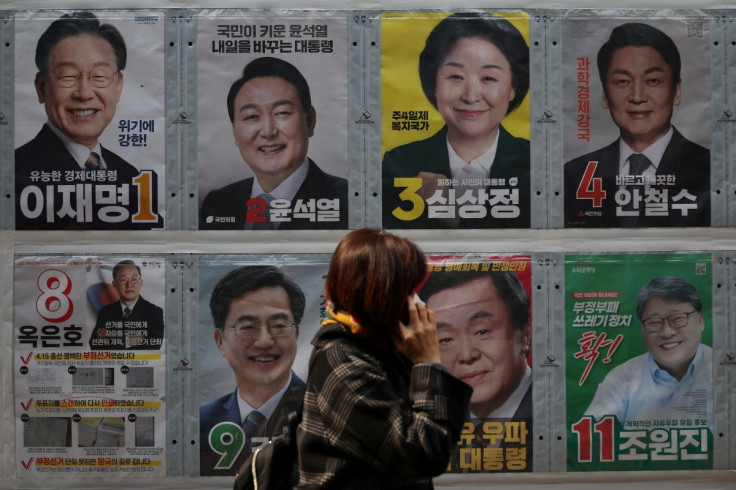A woman walks past posters of candidates for the upcoming March 9 presidential election in Seoul, South Korea, March 7, 2022.   
