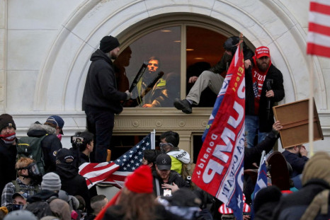 A mob of supporters of then-U.S. President Donald Trump climb through a window they broke as they storm the U.S. Capitol Building in Washington, U.S., January 6, 2021. 