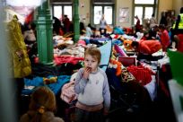 A child eats a cookie as she stands in a temporary accommodation for refugees at the train station, after fleeing Russian invasion of Ukraine, in Przemysl, Poland, March 7, 2022. 