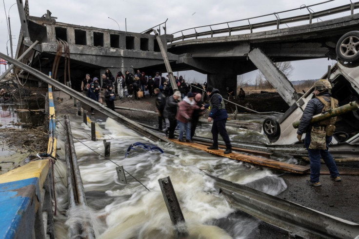 Local residents cross a destroyed bridge as they evacuate from the town of Irpin, after days of heavy shelling on the only escape route used by locals, while Russian troops advance towards the capital, in Irpin, near Kyiv, Ukraine March 7, 2022. 