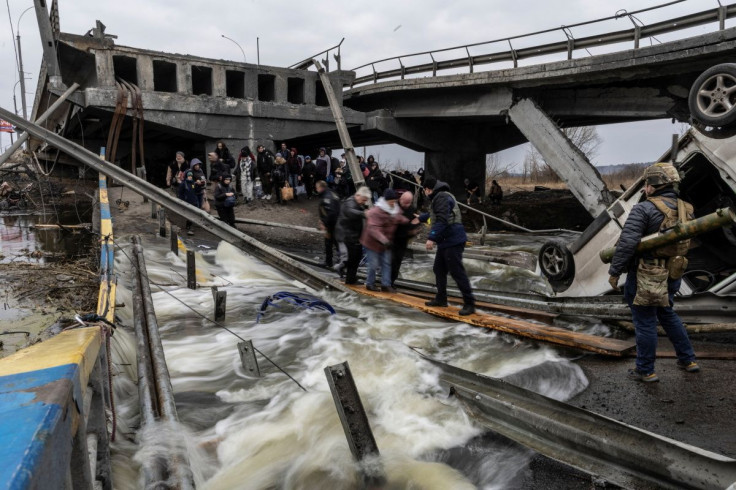 Local residents cross a destroyed bridge as they evacuate from the town of Irpin, after days of heavy shelling on the only escape route used by locals, while Russian troops advance towards the capital, in Irpin, near Kyiv, Ukraine March 7, 2022.