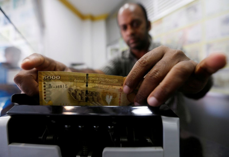A man counts Sri Lankan rupees in a note counting machine at a money exchange counter in Colombo, Sri Lanka September 7, 2018.