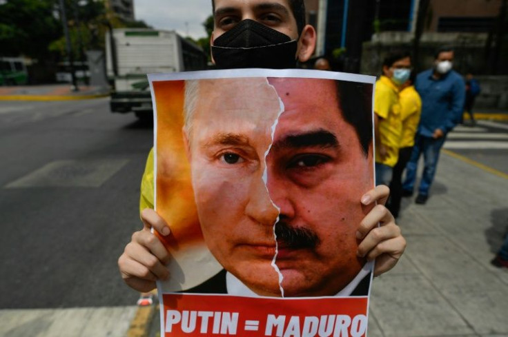A Venezuela opposition protester holds up a poster of President Nicolas Maduro and his Russia counterpart Vladimir Putin