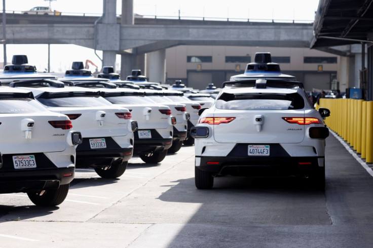 A Jaguar I-Pace electric vehicle drives past some of the Waymo fleet being recharged at Waymo's operations center in the Bayview district of San Francisco, California, U.S. October 19, 2021.   