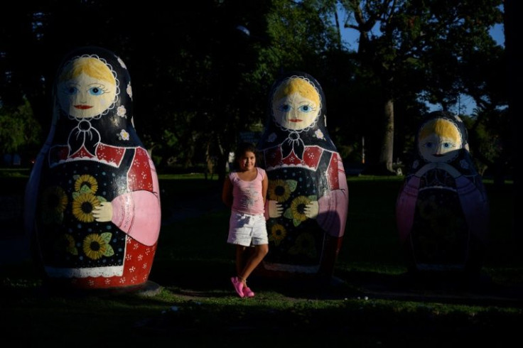 A girl poses with traditional Russian nesting dolls, called matryoshkas, at the Libertad square in San Javier, Uruguay, on March 1, 2022