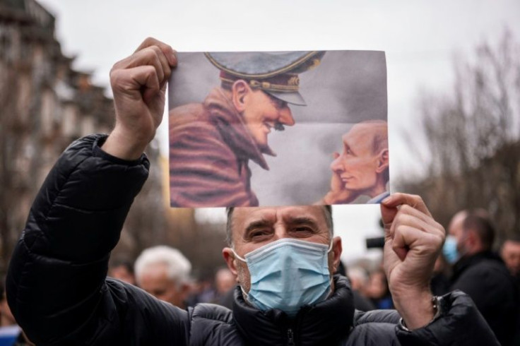 A man holds a caricature depicting Adolf Hitler and Russian President Vladimir Putin during a protest against the Russian invasion of Ukraine in Kosovo on March 7