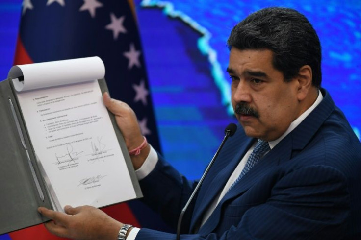 Venezuelan President Nicolas Maduro holding the memo of negotiations that his government and the opposition signed in Mexico last year