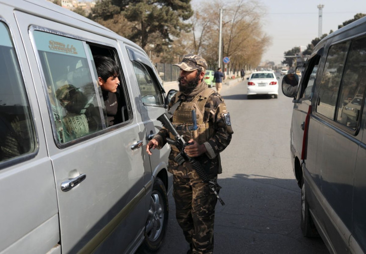 A Taliban fighter searches a car as he guards a checkpoint in Kabul, Afghanistan November 27, 2021.