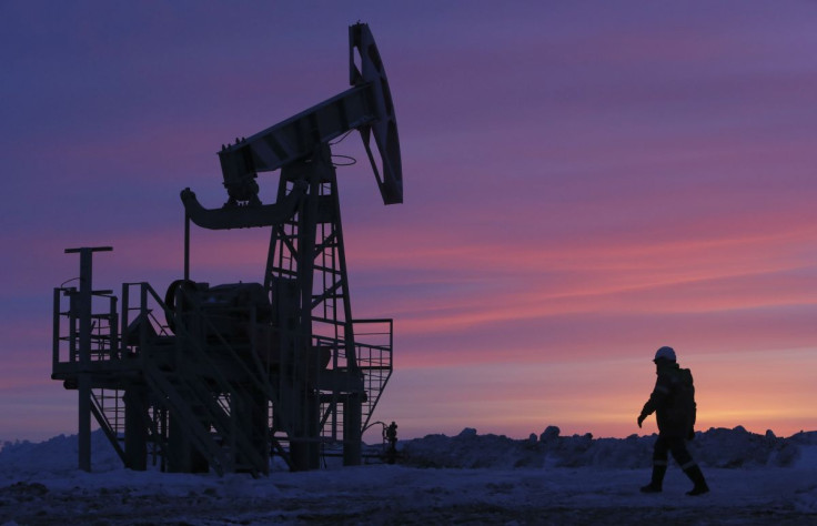 A worker walks past a pump jack on an oil field owned by Bashneft company near the village of Nikolo-Berezovka, northwest from Ufa, Bashkortostan, January 28, 2015.