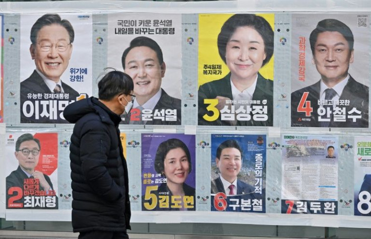 A man walks past posters of South Korea's presidential candidates (top row) in Seoul on March 6, 2022, ahead of the March 9 presidential election
