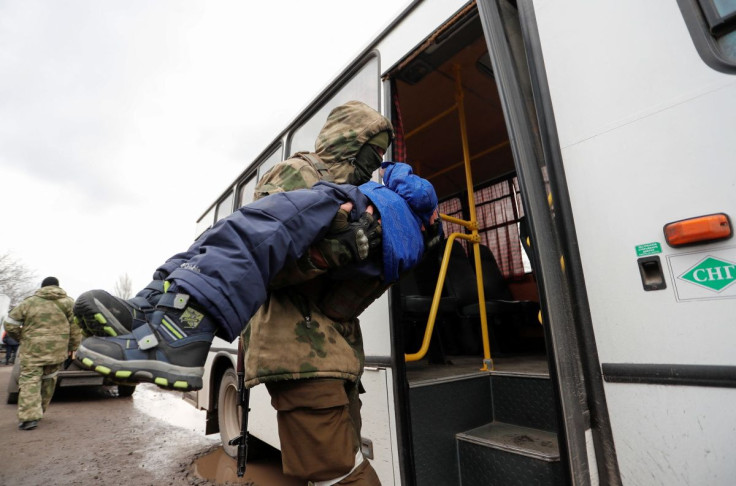 A service member of pro-Russian troops carries a child, who was evacuated from Mariupol area to a refugee camp in the settlement of Bezymennoye, into a bus before the departure for the territory of Russia during Ukraine-Russia conflict in the Donetsk regi