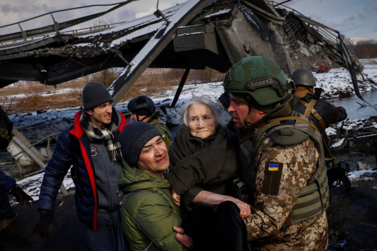 Two men carry a woman as people flee from advancing Russian troops whose attack on Ukraine continues in the town of Irpin outside Kyiv, Ukraine, March 8, 2022. 