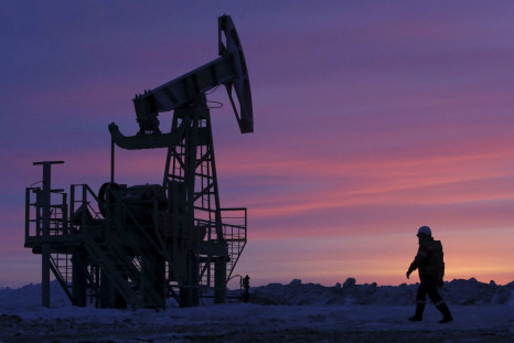 A worker walks past a pump jack on an oil field owned by Bashneft company near the village of Nikolo-Berezovka, northwest from Ufa, Bashkortostan, Russia, January 28, 2015. 