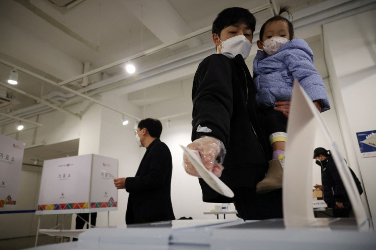 A man holding his child casts his vote at a polling station during the presidential elections in Seoul, South Korea, March 9, 2022.  